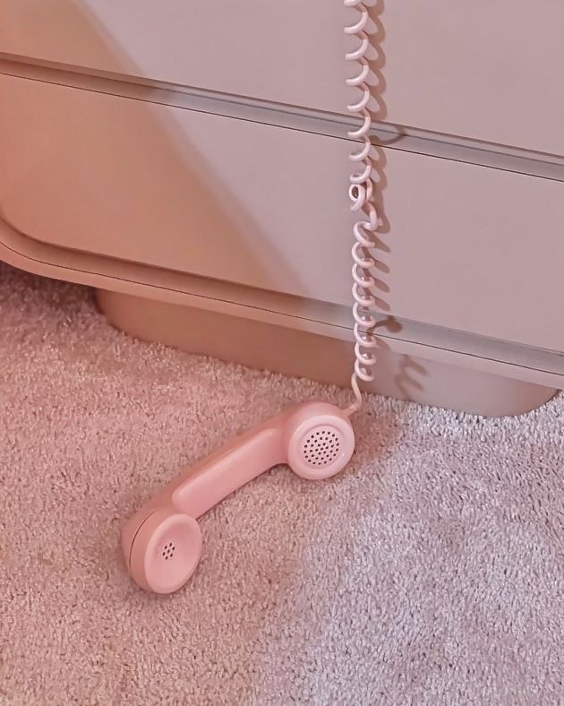 a pink phone is on the floor next to a dresser