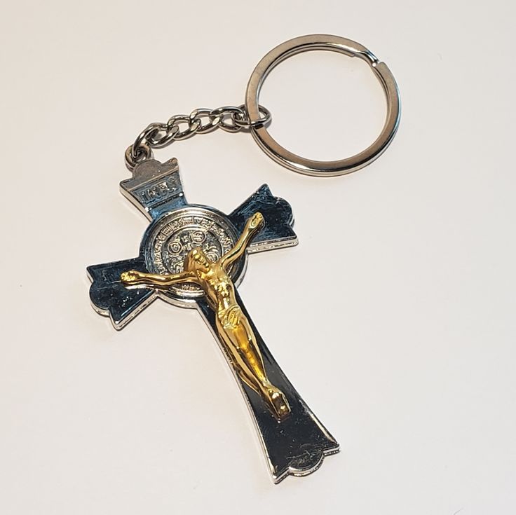 a cross keychain with a crown on it is laying on a white surface