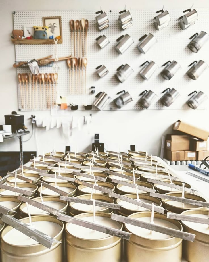 several metal cans are lined up on a table in front of a wall with pegs