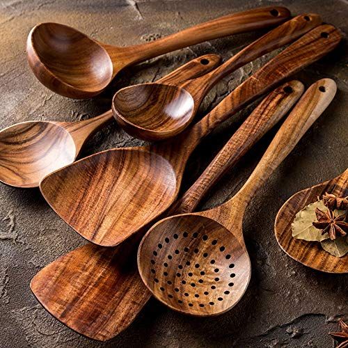 several wooden spoons are lined up next to each other on a stone surface with spices scattered around them