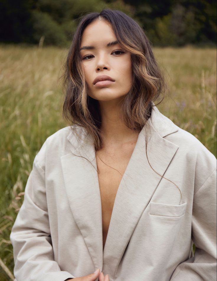 a woman standing in the middle of a field with her hands on her hips and looking off into the distance