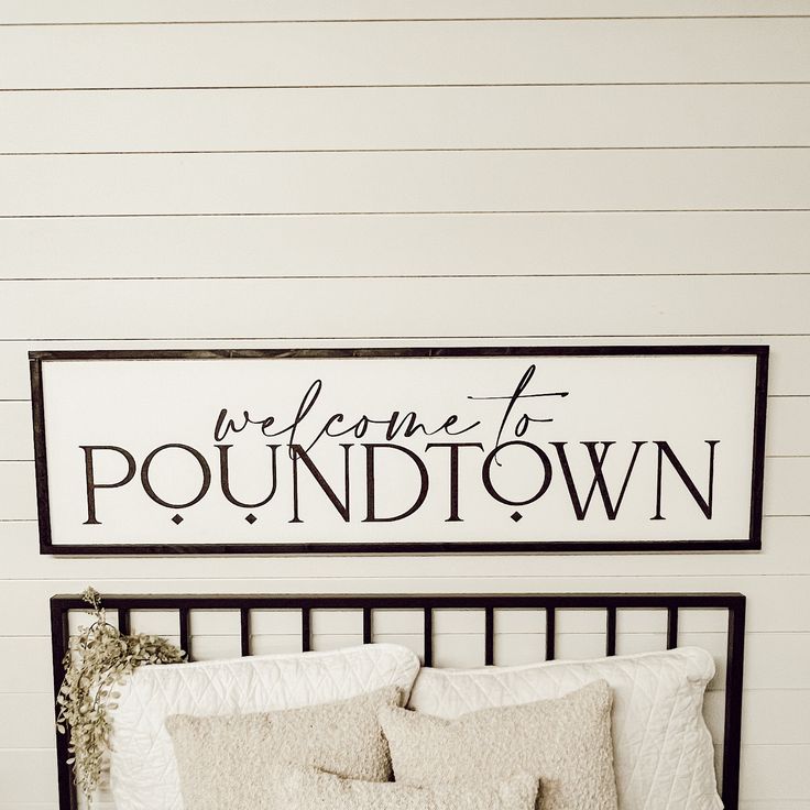 a bed with white sheets and pillows in front of a sign that says welcome to poundtown