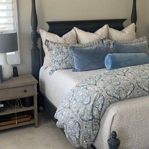 a bed with blue and white comforter in a bedroom next to a night stand