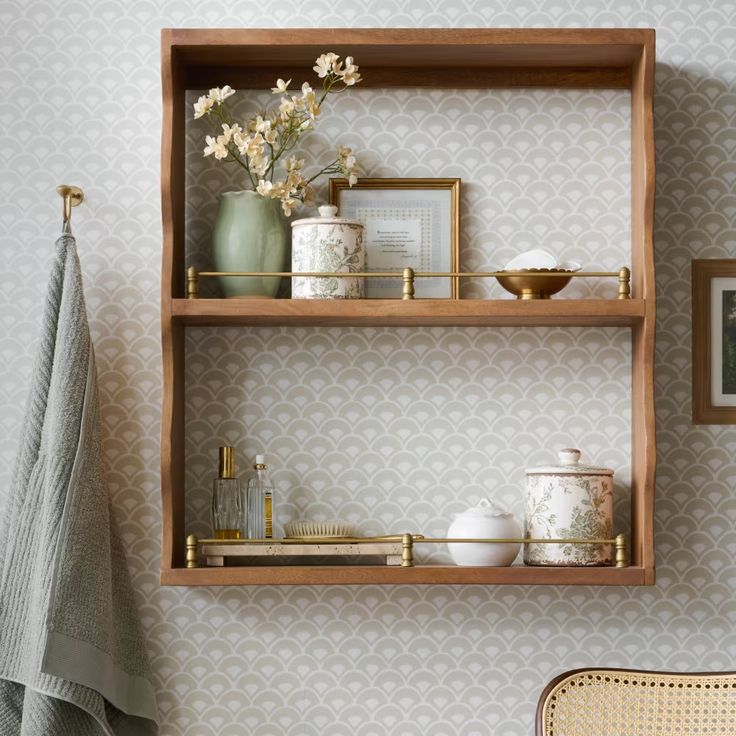 two wooden shelves with pictures and vases on them next to a wall mounted towel rack