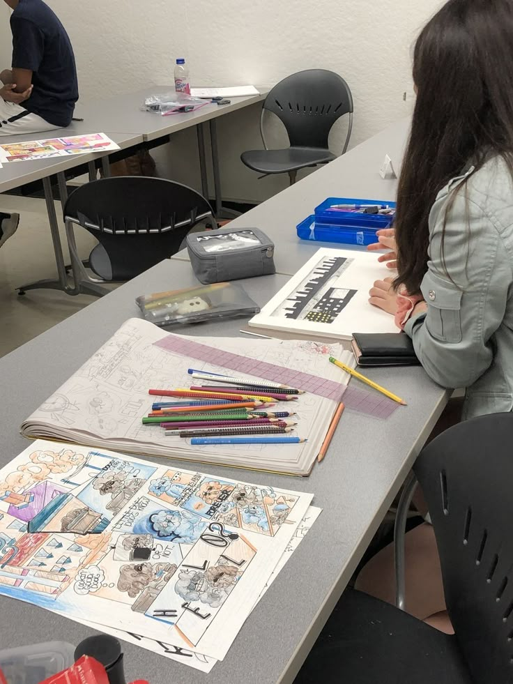 two people sitting at a table with books and pencils