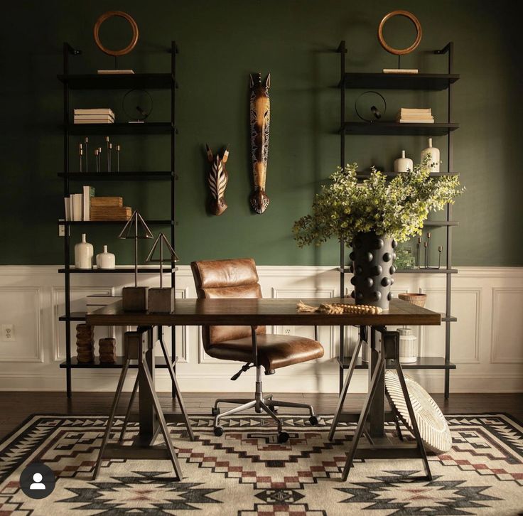 an office with green walls and leather chairs in front of a desk that has a potted plant on it