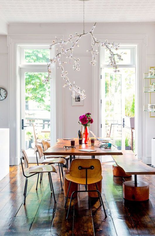 a dining room table with chairs and a vase filled with flowers on top of it