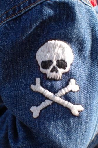 a skull and crossbones embroidered on the back of a pair of blue jeans