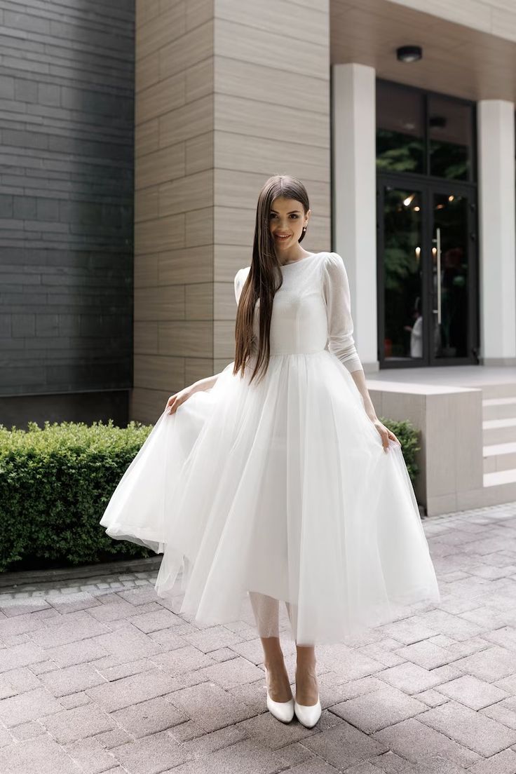 a woman in a white dress is standing outside