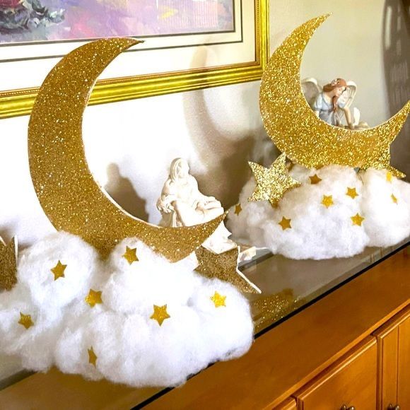 there are clouds and stars on top of the moon in front of an angel figurine