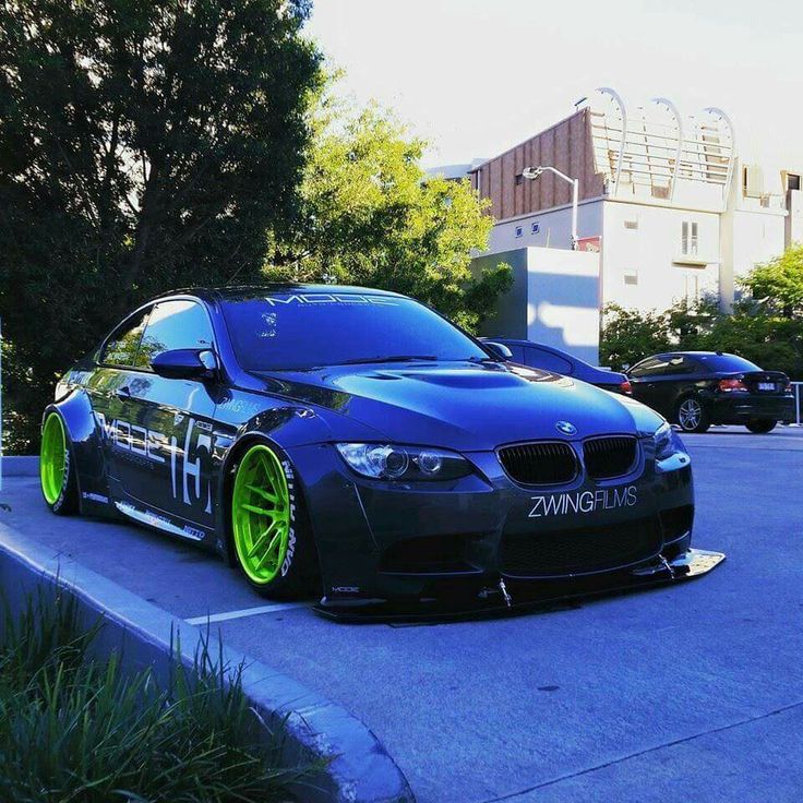 a black car with yellow rims parked in a parking lot