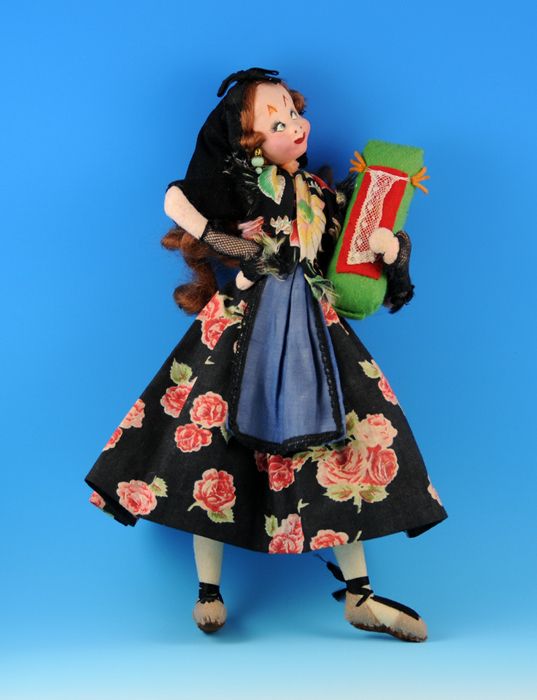 the doll is wearing a black dress and holding a green box with red roses on it