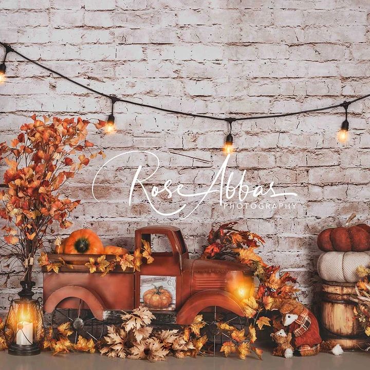 an old truck with pumpkins and fall leaves on the bed is surrounded by lights