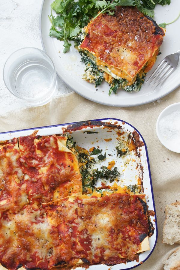 a casserole dish with spinach and cheese on it next to a slice of bread