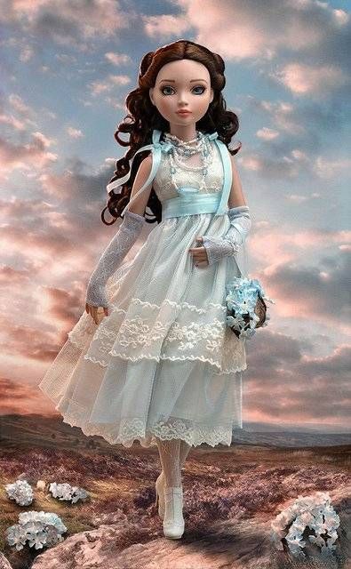 a doll is standing in the middle of a field with flowers and clouds behind her