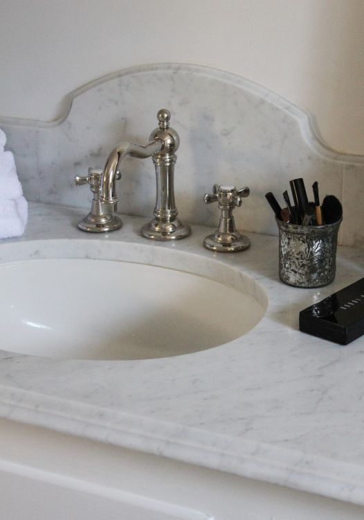 a bathroom sink with two faucets, soap dispenser and toothbrushes