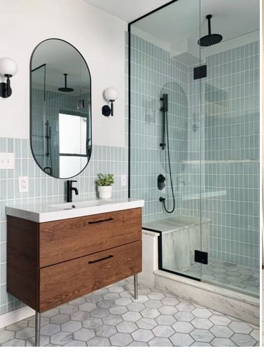 a bathroom with a sink, mirror and stand up shower stall in it's corner