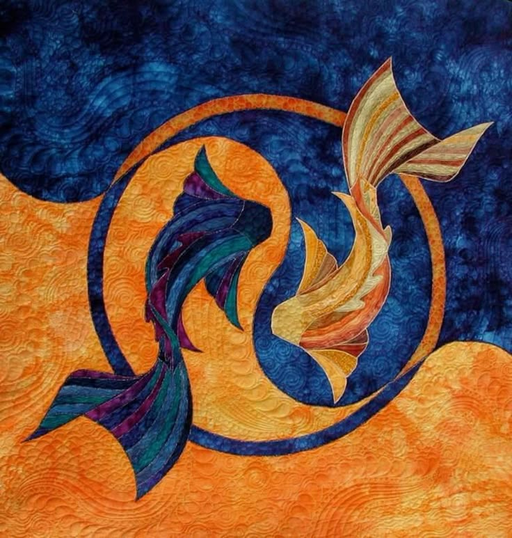 an orange and blue quilt with a fish on it's side, in the middle of a circular design