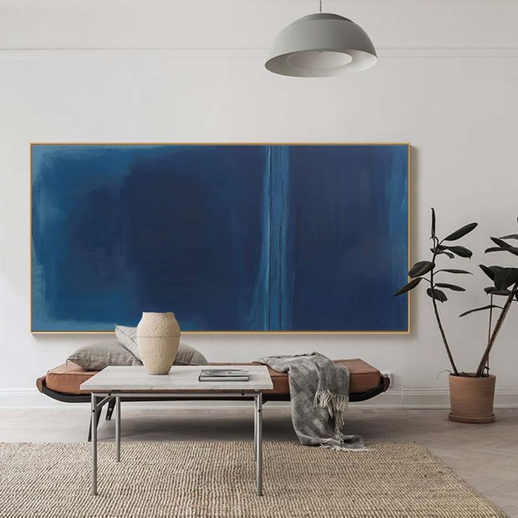 a living room with a large blue painting on the wall and two potted plants