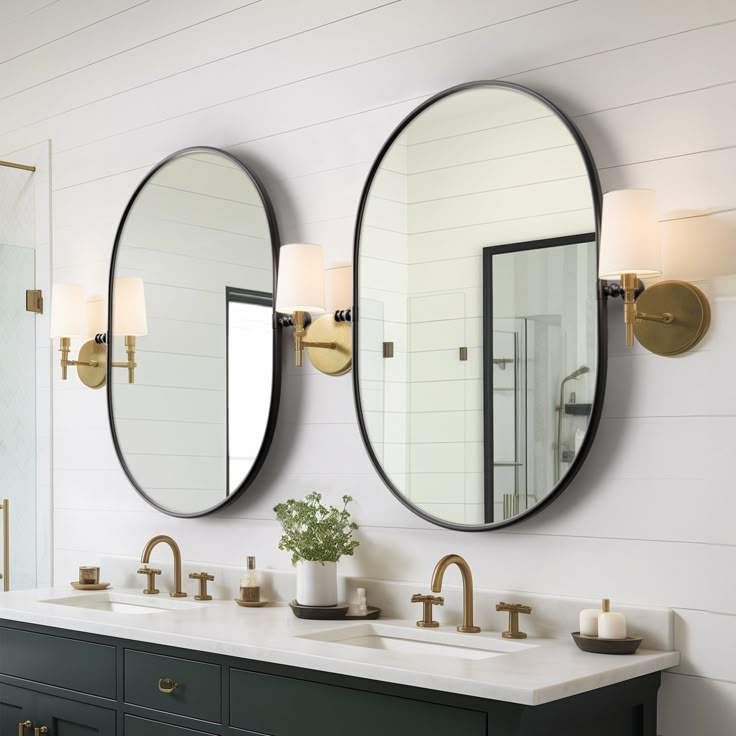 two round mirrors are hanging above the double sink vanity in this bathroom with white walls and gold fixtures