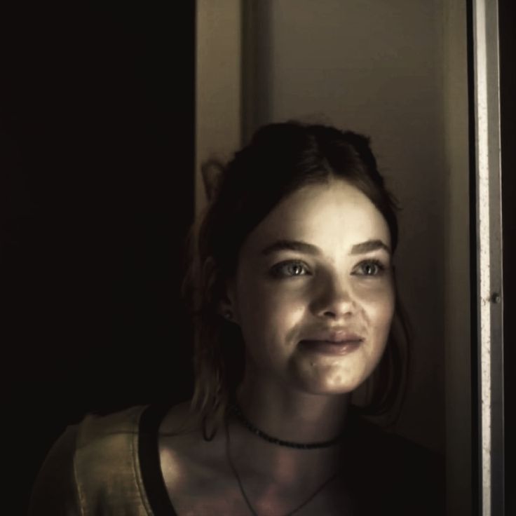 a young woman with blue eyes is smiling at the camera while wearing a black necklace