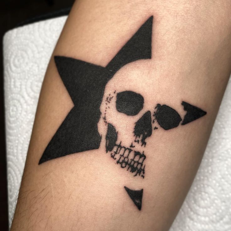 a skull and star tattoo on the left arm, with an arrow in the middle