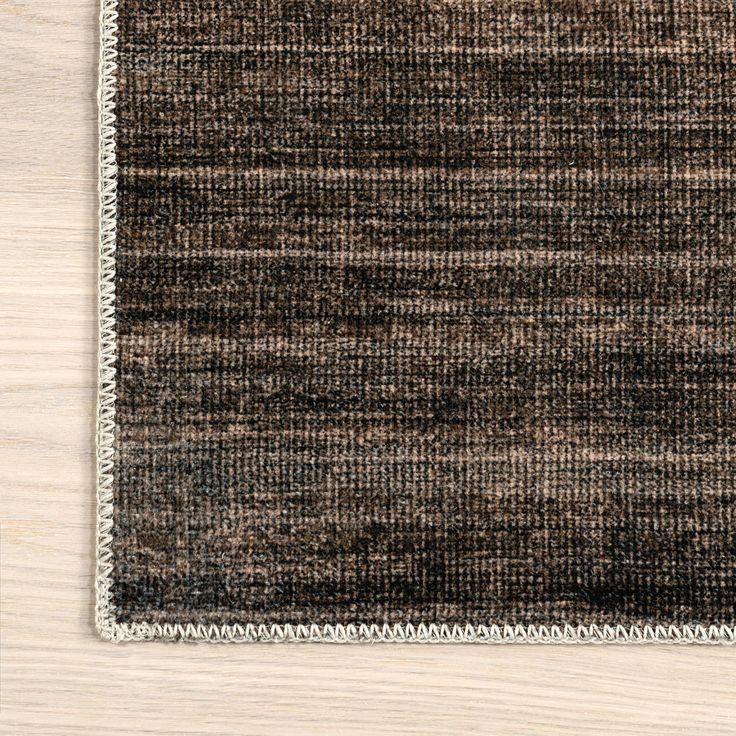 an area rug on top of a wooden floor with white trimmings and fringe