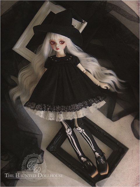 a doll with long white hair wearing a black dress and hat