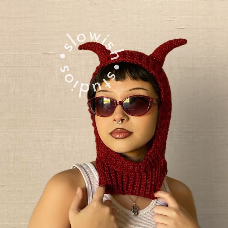 a woman wearing a knit devil hat and sunglasses