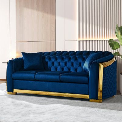 a living room with a blue couch and gold trimmings on the armrests