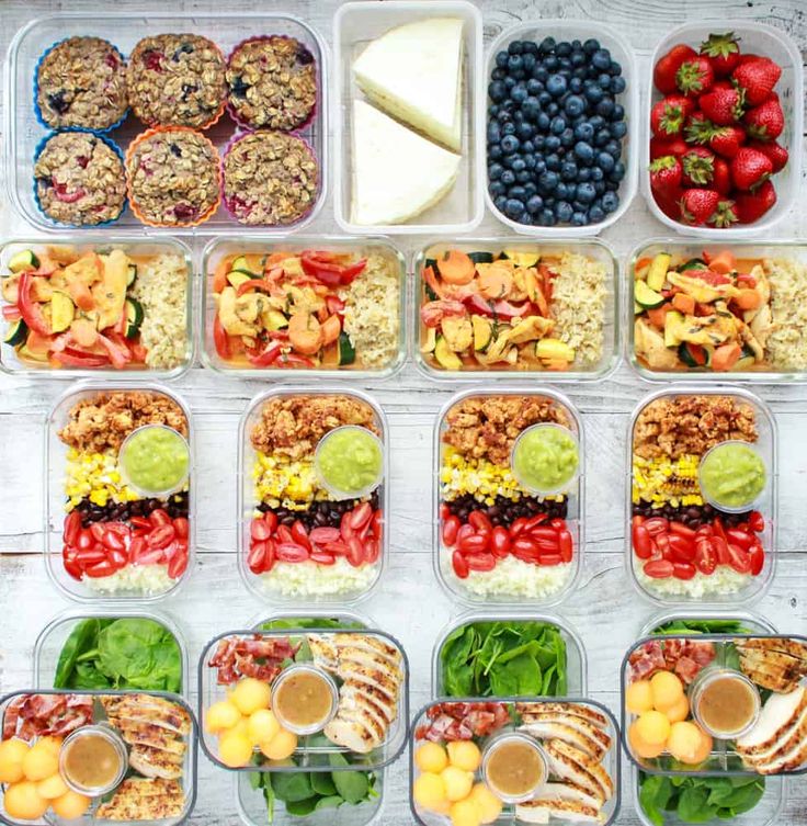 several plastic containers filled with different types of food including fruit, vegetables and crackers