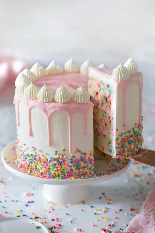 a white cake with pink frosting and sprinkles