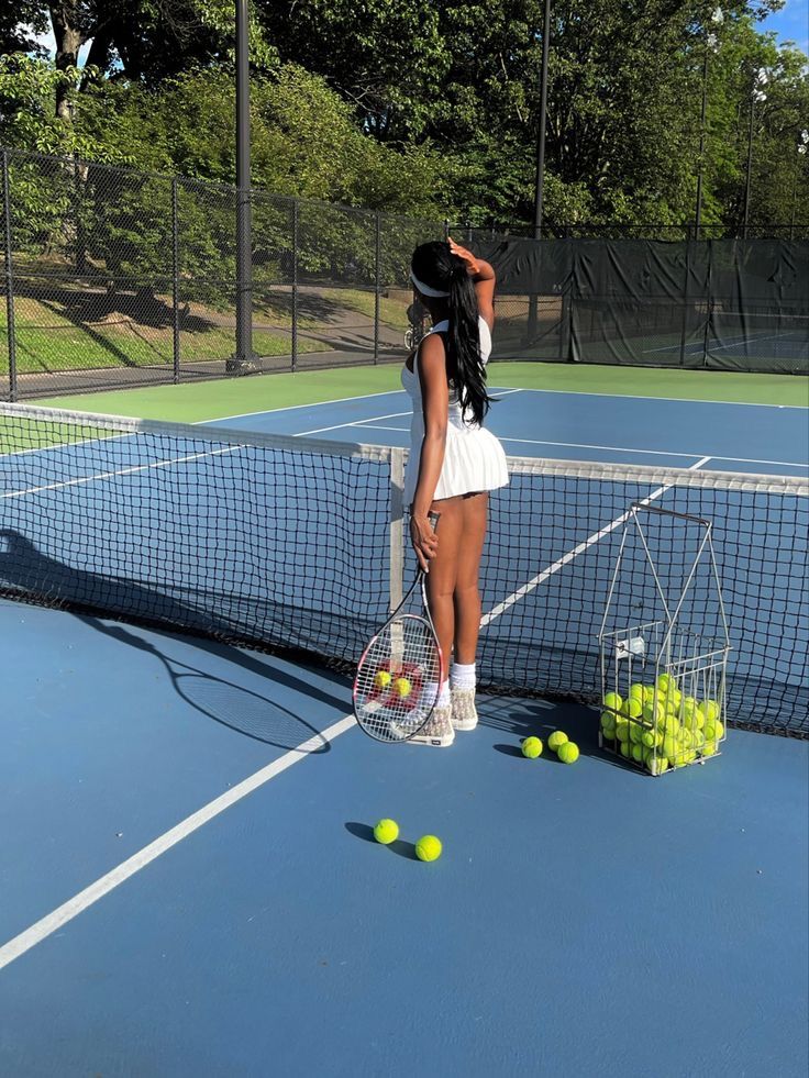 a woman standing on top of a tennis court holding a racquet and ball