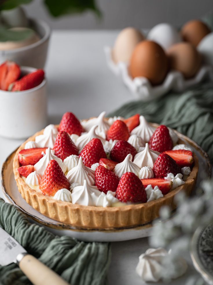 there is a pie with strawberries on it and some eggs in the back ground