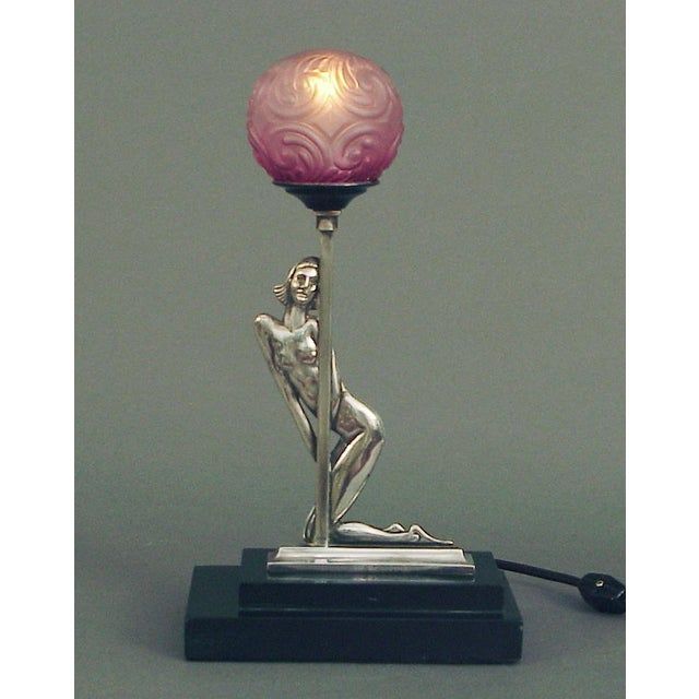 a lamp that is sitting on top of a stand with a pink ball in the shape of a woman