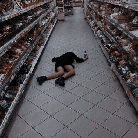 a woman laying on the floor in a grocery store aisle with her head down and hands behind her back