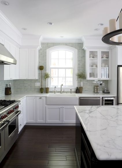 a white kitchen with marble counter tops and stainless steel stove top oven, dishwasher, and sink