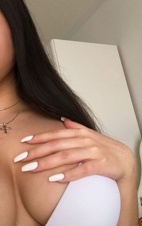 a woman with long black hair and white nails is holding her hand on her chest