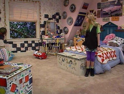 a woman standing in a bedroom with lots of stuff on the floor and furniture around her