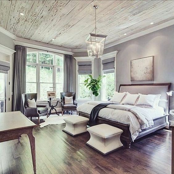 a large bedroom with wood floors and white furniture in the center, along with two windows