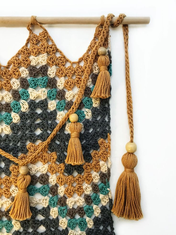 a crocheted wall hanging with tassels and beads