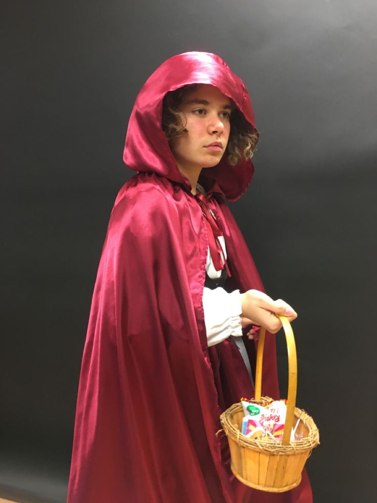 a man dressed in a red cape and holding a basket with candy bars on it