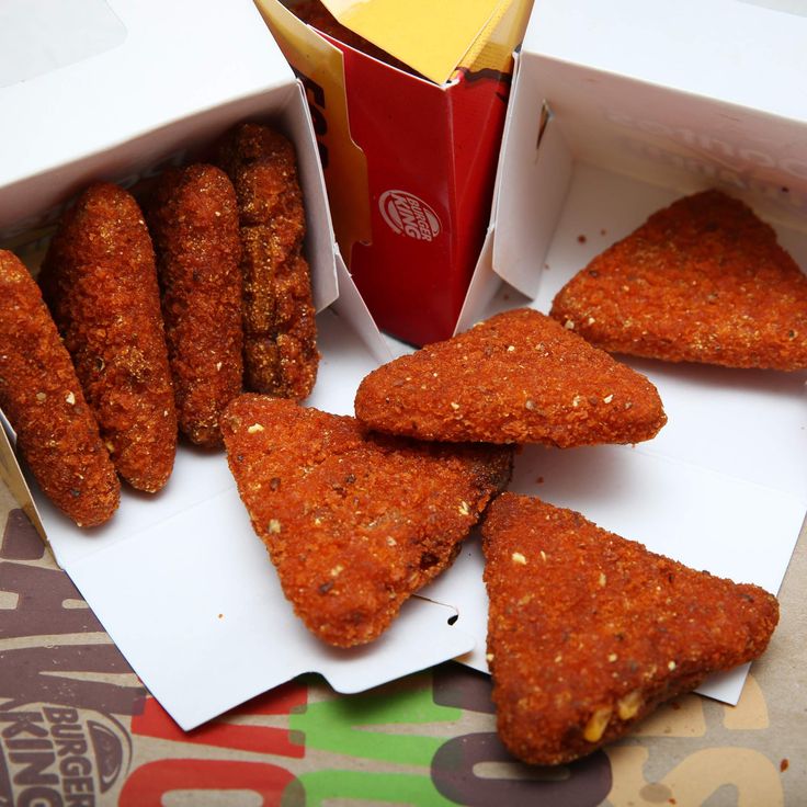 several pieces of food sitting in a box next to a cup and paper napkins