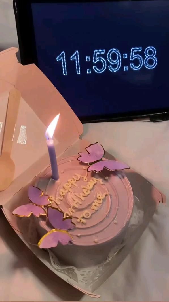 a birthday cake sitting on top of a table next to a cell phone and clock