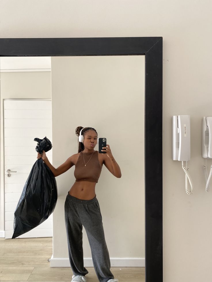 a woman taking a selfie in front of a mirror holding a bag and cell phone