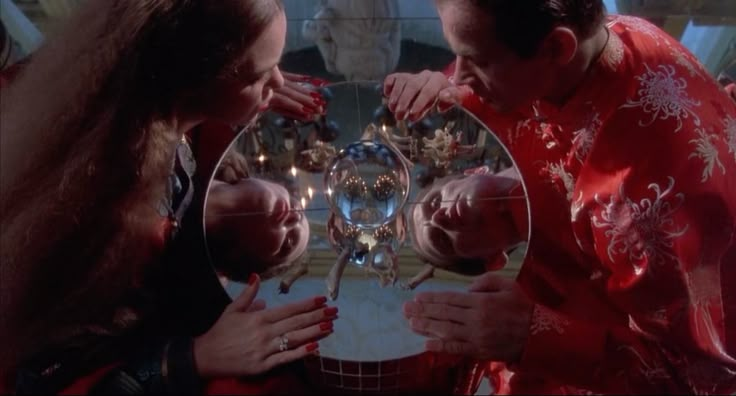 a man and woman looking at their reflection in a mirror with christmas decorations on it