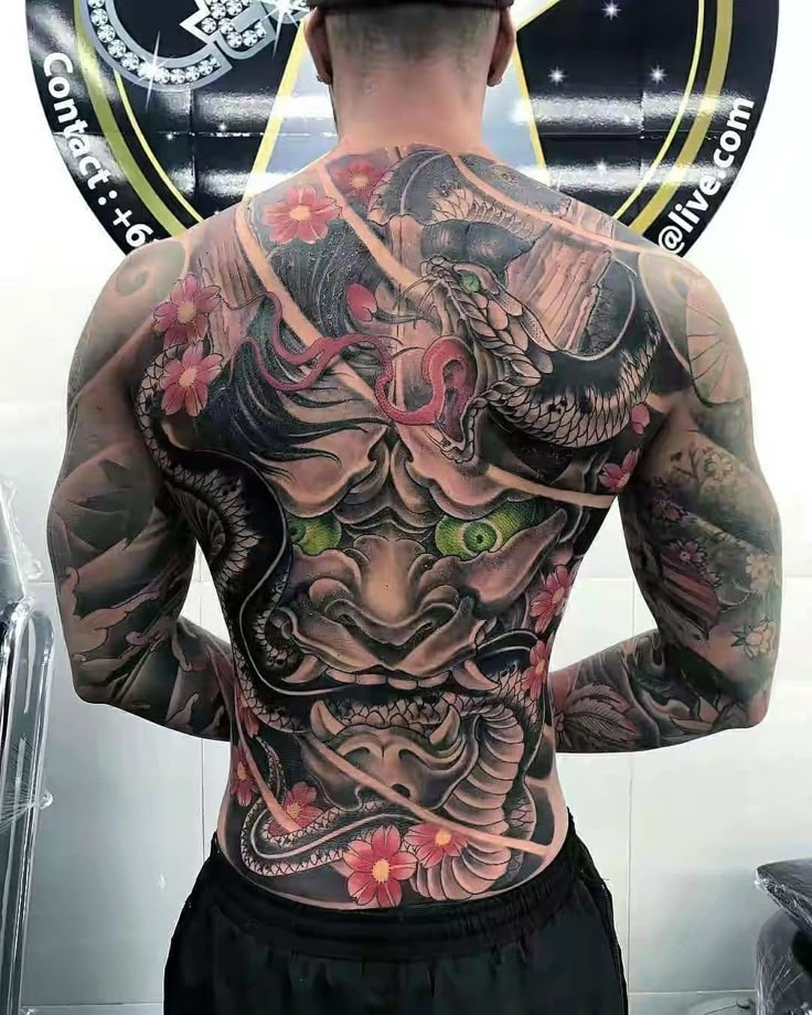 a man with tattoos on his back standing in front of a mirror