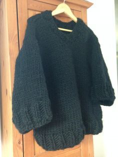 a black sweater hanging on a wooden door