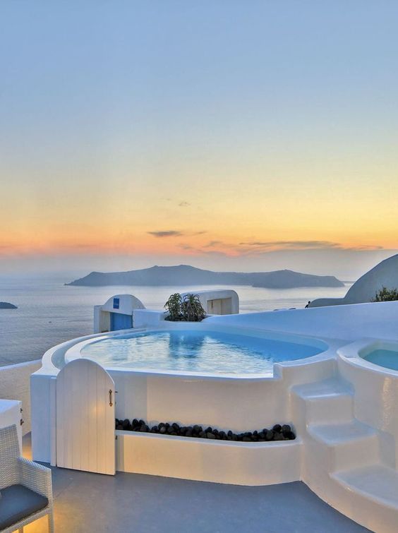 an outdoor jacuzzi overlooking the ocean at sunset