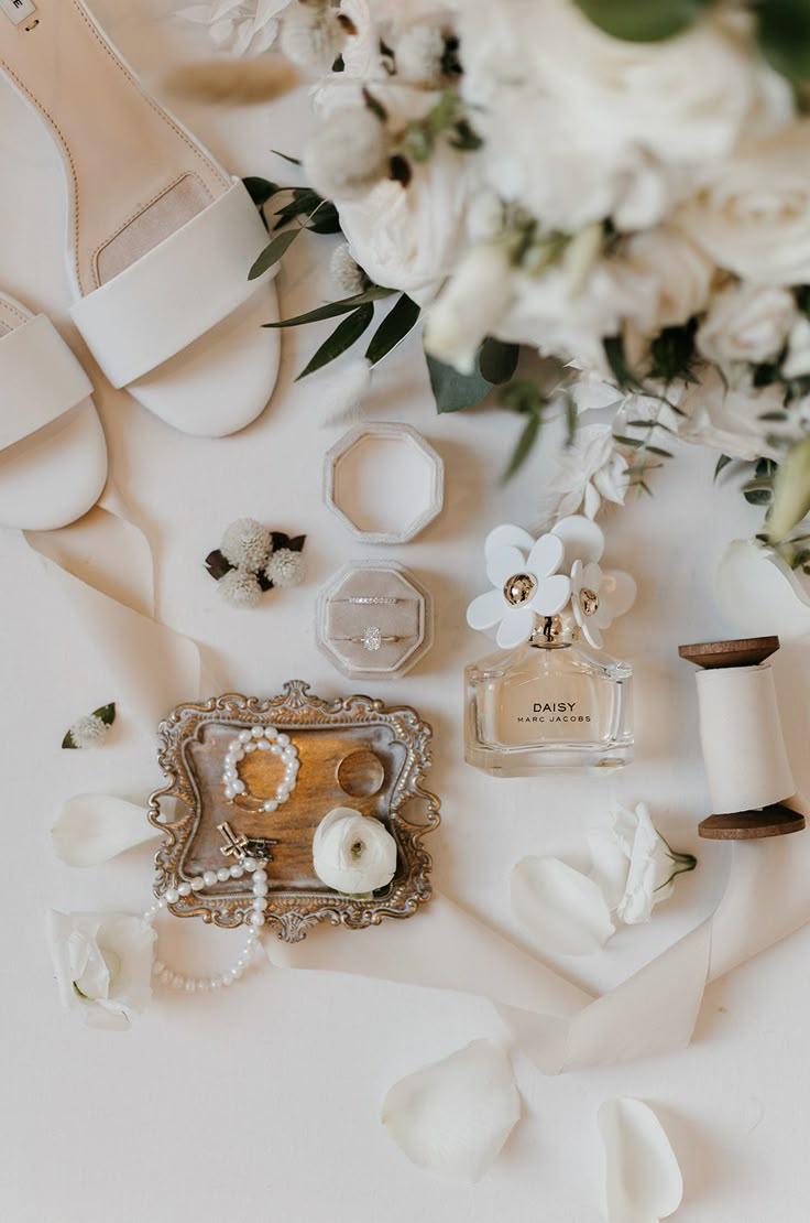 white flowers and wedding accessories laid out on a table with the bride's shoes